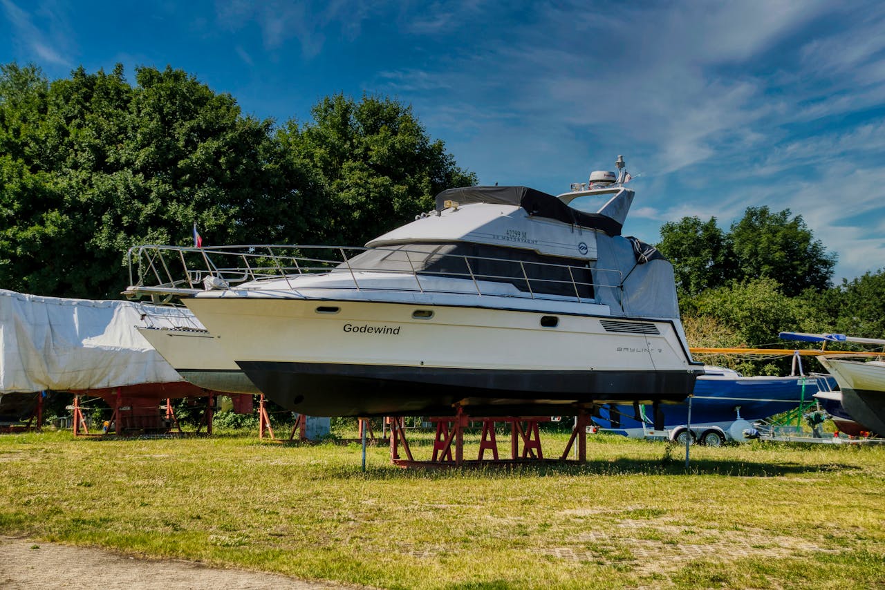 A luxury yacht named 'Godewind' displayed on land with a clear sky and trees in the background.